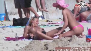 Blondinen cremen sich am Strand ein und küssen sich